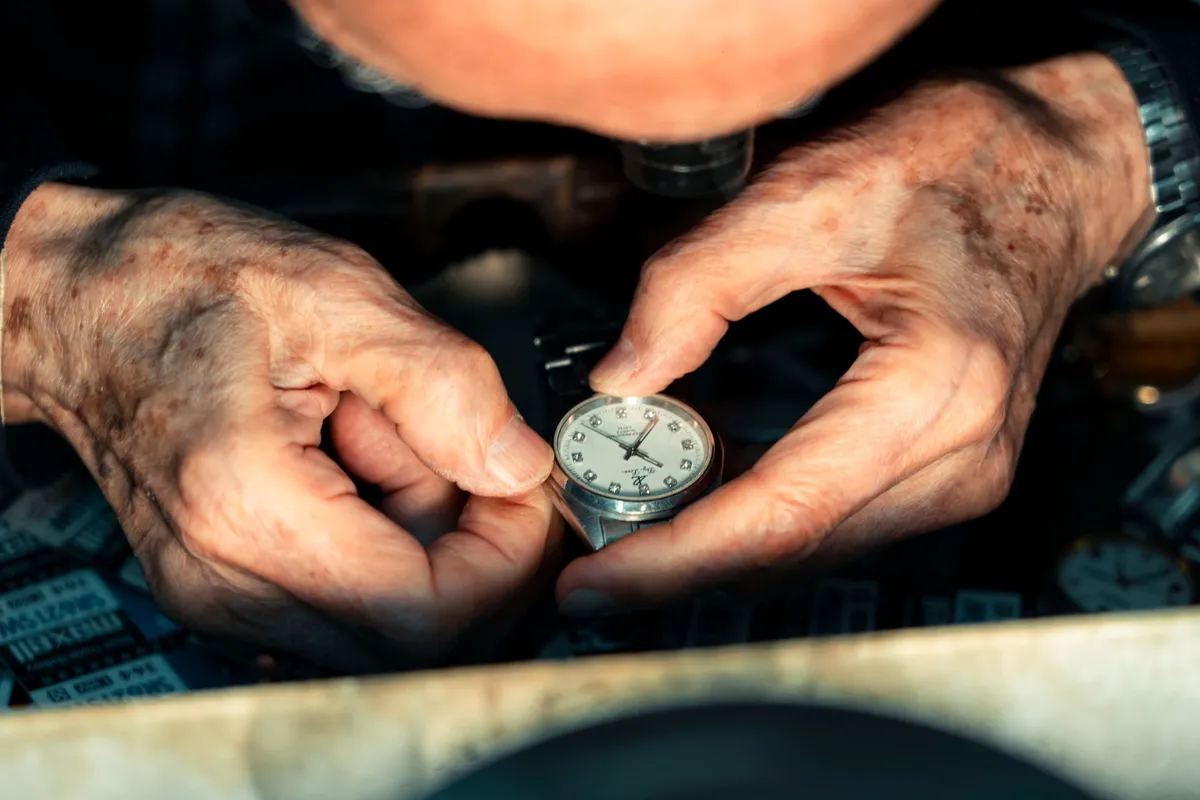 Two hands holding a wristwatch up close